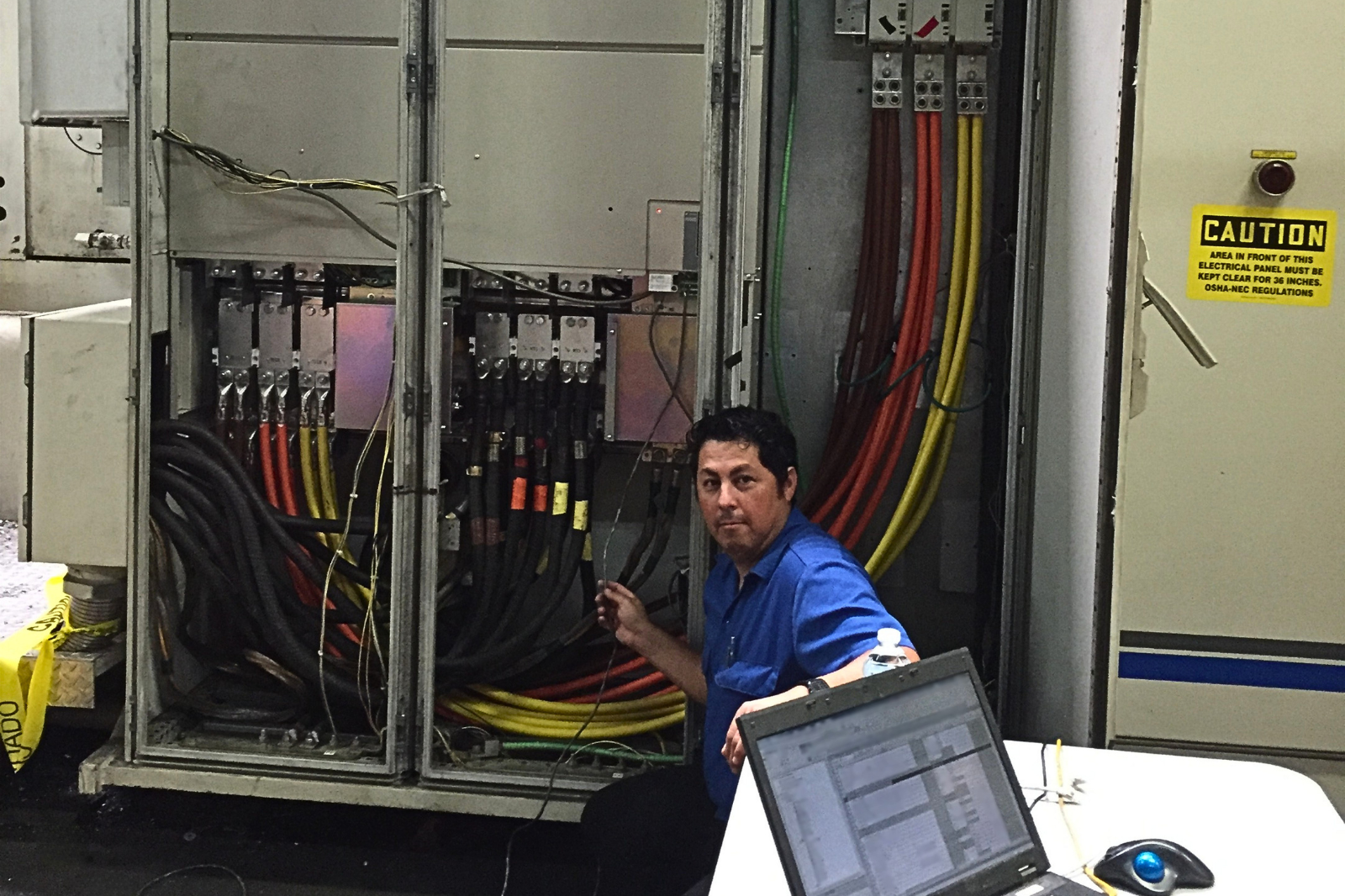 Technician commissioning an Allen-Bradley to Yaskawa drive retrofit inside a large industrial control cabinet