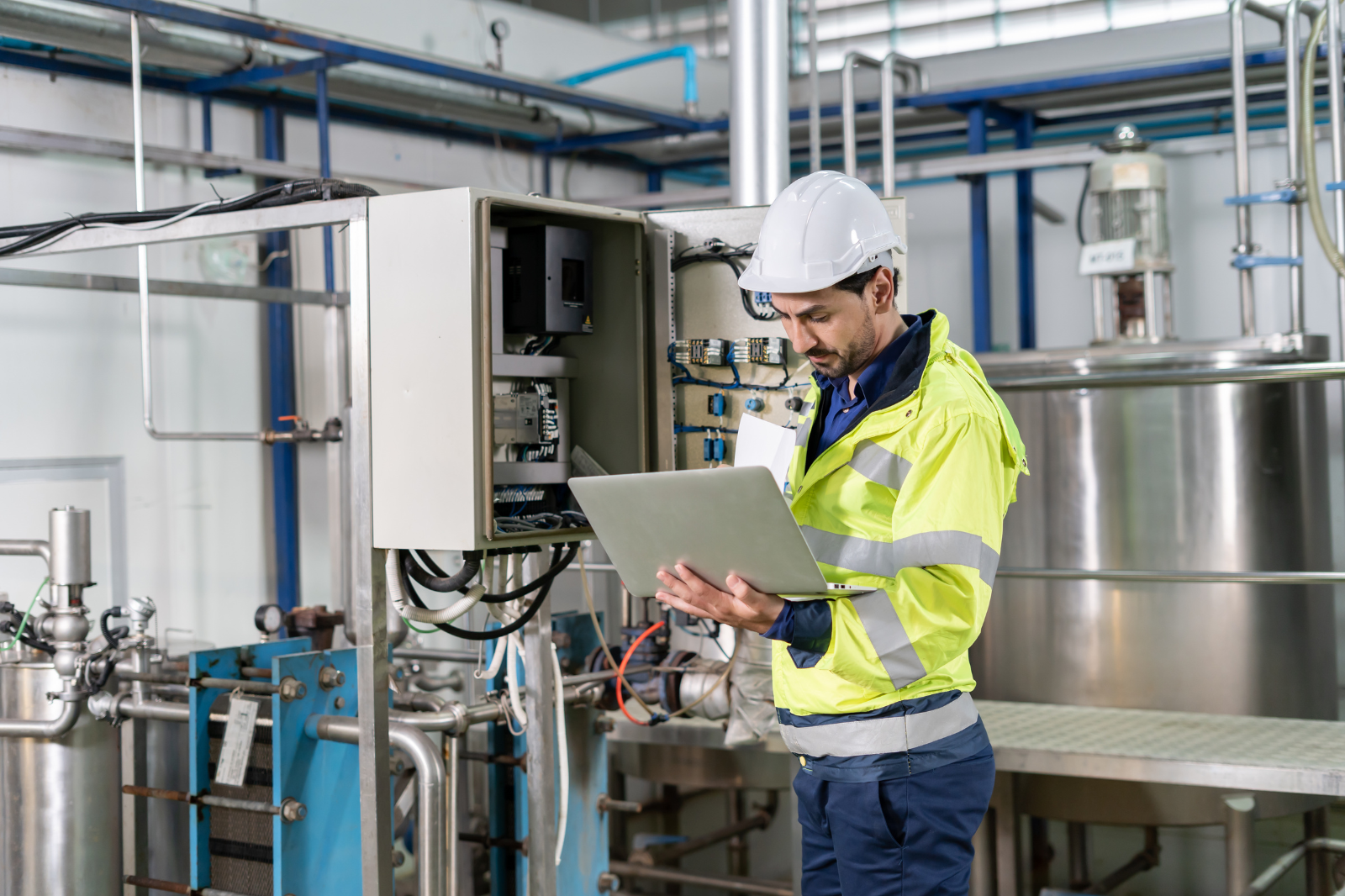 Technician reviewing an industrial control cabinet during a PLC upgrade