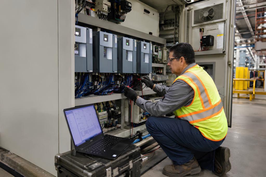 Technician troubleshooting an industrial motor control cabinet for a soft starter or VFD application